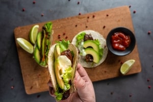 Man Holding A Bite of Fresh Taco with Avocado