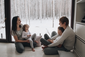 Family Sitting at Window and Looking at Winter Forest